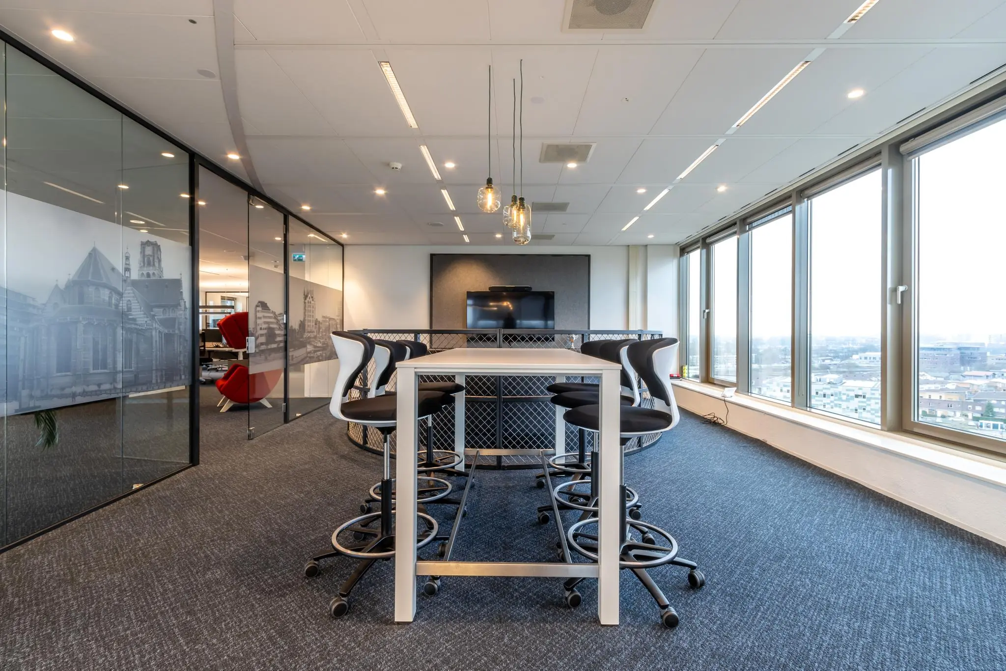 Moderne vergaderruimte met hoge tafel, designstoelen en grote ramen met uitzicht over Fascinatio Boulevard.